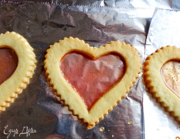 Третье сердечко с дырочкой положить на фольгу,  засыпать толченым леденцом и поставить на несколько минут в духовку не верхнюю полку, чтобы леденец растаял. После того как карамель застынет, аккуратно снять фольгу, а получившееся окошко разрисовать, как вам понравится. 