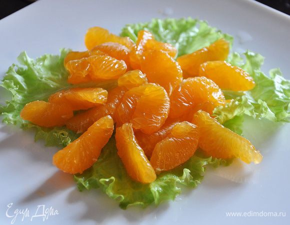 Выложить листья на блюдо. Сверху-очищенные от пленок дольки мандарина.