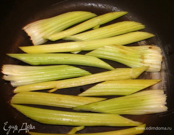 В глубокую сковороду выложить стебли сельдерея. Они не датут роллам пристыть ко дну и усилят вкус! 