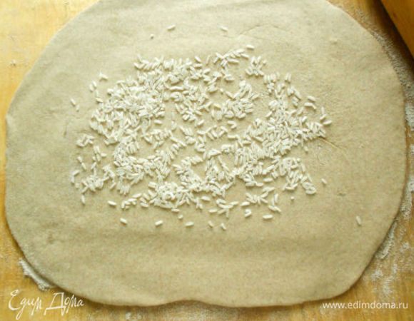 Раскатайте тесто в пласт 30х40 см, оставьте середину немного толще, около 8 мм.
Положите сырой рис на середину теста, он возьмёт лишнюю влагу из рыбы.