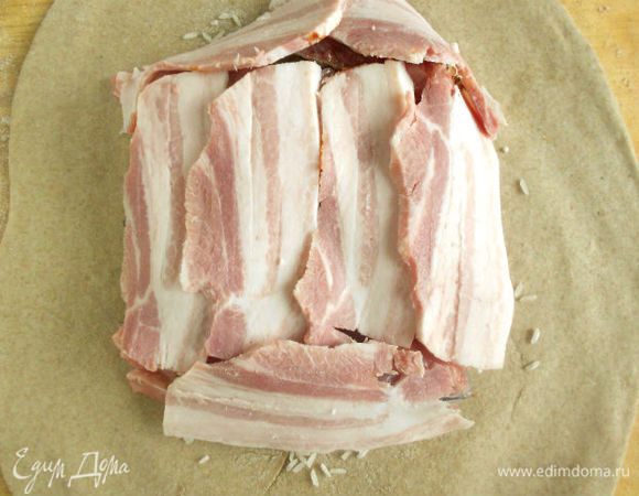 Пластинами бекона накройте всю поверхность рыбы. 
Смочите водой края теста.