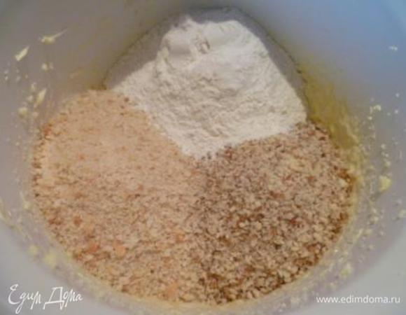 Добавить муку, бисквит, измельченный в крошку, измельченный миндаль, кардамон и миндальную эссенцию.
