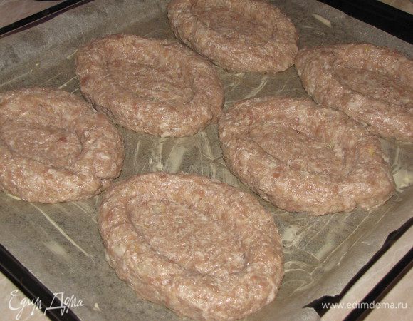 Котлетки немного приплющиваем и с помощью столовой ложки формируем посередине углубления. Углубления должны быть достаточно большими, чтобы в дальнейшем туда поместилось яйцо. Получаются вот такие лодочки. Ставим наши лодочки в духовку, разогретую до 180 град на 20 минут.