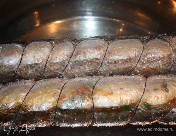 Плотно заворачиваем в несколько слоев пищевой пленки. Края завязать с двух сторон как «конфетку» и перетянуть ниткой по кругу. Это мы делаем для того, чтобы убрать воздух и не дать образоваться воздушному пузырю.
Нашу рыбку отправляем в кипящую воду на 35 минут.