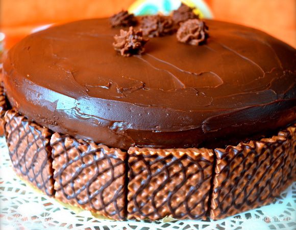 Тогда я посоветовалась с Евой, и на следующий раз дала глазури подольше остыть в холодильнике... Как только ганаж немного загустел, я нанесла его на поверхность торта и распределила с помощью лопатки, покрыв им также и бока торта. Для украшения по всему периметру торта, по низу выкладываем "декоративные" тонкие вафли, покрытые шоколадом (как на фото!). Остатки ганаша можно взбить с помощью миксера и отсадить на торт "розочи" с помощью кондитерского мешка. На Ваше усмотрение... )))