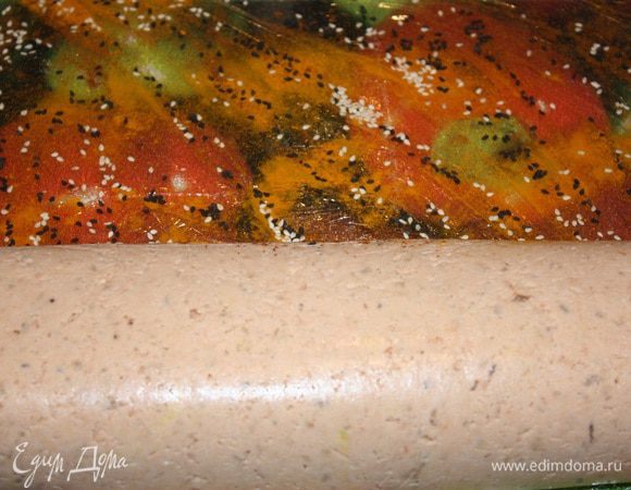 Разворачиваем рулет. Пленку посыпаем куркумой, паприкой, кунжутными семечками (белые и черные) и обваливаем во всем этом рулет.