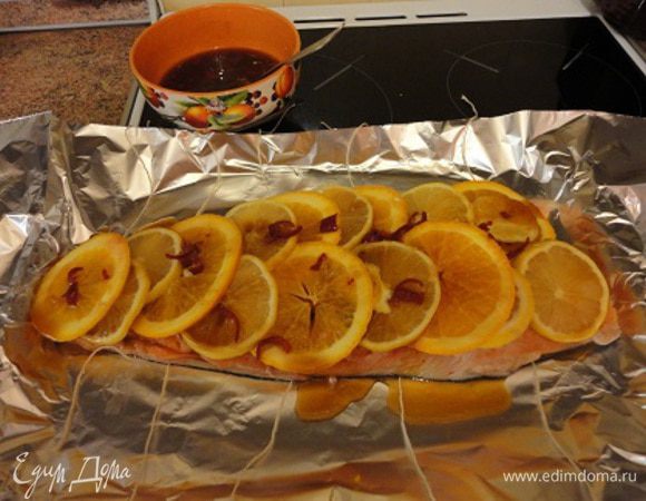 Положить первый кусок филе на фольгу. Нарезать 2-й лимон и апельсин дольками, выложить их на филе и немного полить маринадом.