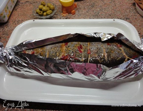 Достать рыбу из холодильника и подождать, пока она не достигнет комнатной температуры. Полить рыбу еще раз маринадом и потом обернуть ее фольгой так, чтобы верх остался открытым. Разогреть духовку до 200 градусов и запекать 45 минут.