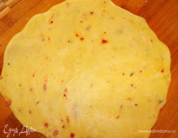 Взять один кусочек, раскатать в виде круга толщиной 1.5-2 мм. Тесто не прилипает, пользоваться дополнительно мукой не нужно.