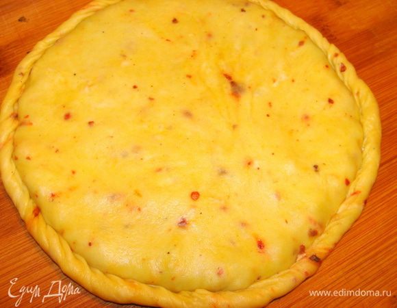На другой доске раскатать точно такой же пласт в виде круга. Выложить его поверх начинки. Края аккуратно защипить. Сковороду разогреть без масла. Выложить на нее лепешку швом вниз. Жарить на медленном огне, до образования золотистой корочки. Перевернуть и жарить пока лепешка не вздуется. Выложить на деревянную доску.