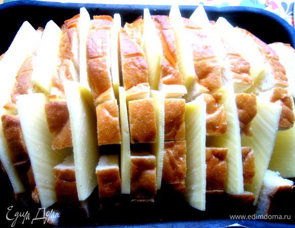 Помещаем хлеб в смазанную форму,раздвигаем слегка куски и всовываем по два кусочка сыра между ломтями.