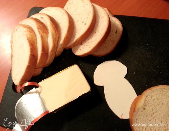 Начнём с белого хлеба. Вырезаем из картона шаблон гриба и накладываем на куски хлеба.