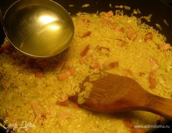 После этого уменьшаем огонь и начинаем понемногу вливать горячий бульон (по 1 половнику за раз). Помешиваем рис. Следующий половник добавляем, когда предыдущий впитался. Так продолжаем до готовности риса (аль-денте).
