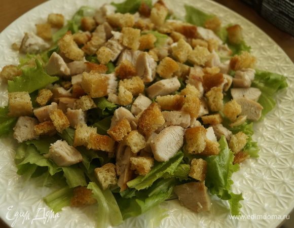 Зеленый салат порвать руками на кусочки и выстелить на тарелку. Положить куриное филе, порезанное кубиками, и сухарики.