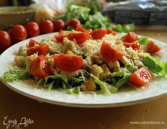 Выложить помидоры черри, разрезанные на 4 части. Подавать салат сразу, чтобы не размокли сухарики.