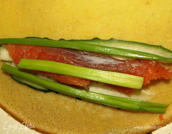 Огурец, семгу режем длинными ломтиками. Зеленый лук (только зеленую часть). Укладываем на блинчик и сворачиваем.