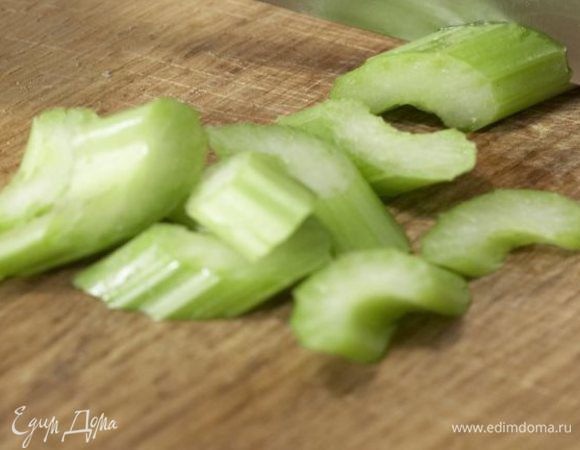 Зубчик чеснока разрезать пополам и натереть им салатную миску. Избавить от самого чеснока. Белую часть зелёного лука нарезать тонкичи кольцами. Тонкими пластинами порезать сельдерей и фенхель. Отправить их в салатную миску.