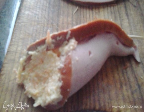 Сворачиваем каждый кусочек колбасы бутончиком, наполняем начинкой и закрепляем половинкой зубочистки. 