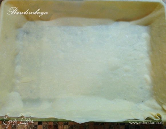 Форму для запекания (у меня 35 на 24 см)  смазать маслом (сливочным). Большую часть теста раскатать скалкой в очень тонкий пласт размером большим чем форма. Выстелить форму раскатанным тестом так, чтобы края теста свисали с формы.