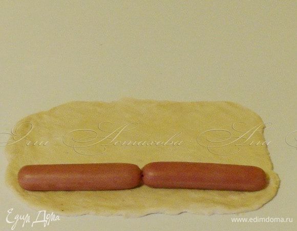 Беру вторую часть и также раскатываю. 

Выкладываю сосиски на один край. 
