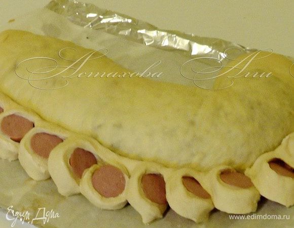 И перекладываю этот рулетик на то место где должна быть грива (вдоль головы вплотную к первому рулету). 

Разворачиваю красиво кусочки теста с сосиской (поворачивайте, чтобы была видна сосиска – это будет грива лошади).