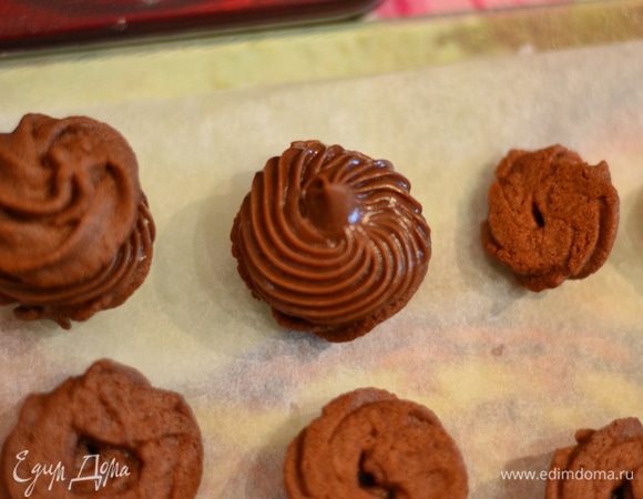 И отсадить из кондитерского мешка на каждую половинку небольшую порцию крема. Соединить второй половинкой. Можно печенье украсить растопленным шоколадом. Печенье охладить. 