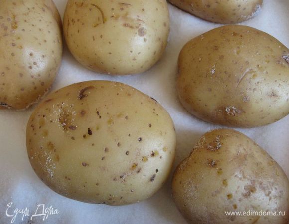Положить на противень на толстый слой соли. Наколоть вилкой, чтобы кожура не потрескалась. Поставить противень в разогретую до 200 градусов духовку на 1 ч. Может понадобиться чуть больше времени, необходимо проверить картошку, проколов вилкой.