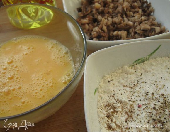 В миску, где находится мука, добавить соль, черный молотый перец и мускатный орех.
В другую миску разбить яйца, взбить их вилкой. Шампиньоны мелко порезать, отжать жидкость.
