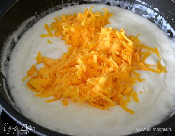 В другой сковороде или сотейнике приготовить соус бешамель: растопить сливочное масло и обжарить муку на среднем огне за пару минут, вливая порциями горячее (!!!) молоко, уварить соус, постоянно помешивая на слабом огне. Помешивая, в готовый соус всыпать чеддер (отложив горсть для посыпки), дать сыру расплавиться, посолить и поперчить по вкусу.