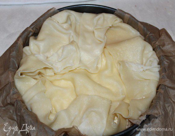 Накрыть начинку следующим коржом и повторить слой сыра и слой масла. Последний корж сыром не посыпаем. Завернуть свисающие край к центру. 