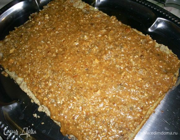 Приступаем к сборке торта. На блюдо кладем пласт бисквита срезом вверх, на него выкладываем половину карамельной прослойки, равномерно ее распределяем по поверхности.