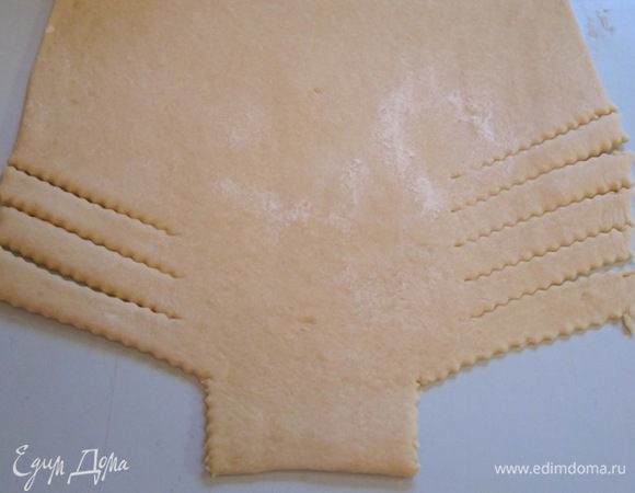 В это время тесто уже поднялось, можно заняться им. Тесто раскатать в прямоугольный пласт размером приблизительно 35х38 см. Края с двух сторон разрезать на полоски шириной 2 см.