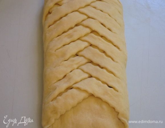 Заплести косу из теста, накладывая полоски поверх начинки одна на другую. Коса должна быть достаточно плотной.