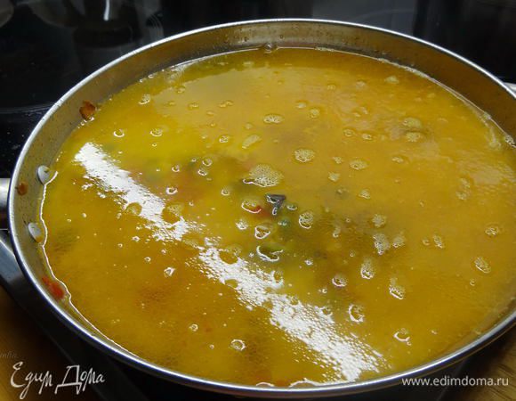 Залить рыбным бульоном, примерно на ширину 2-х пальцев от риса. Закроем крышкой (откроем отверстием для выхода пара) и переключим на маленький огонь.