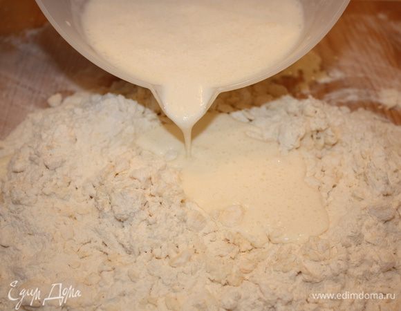Выливаем подготовленную смесь в муку с маргарином и быстро замешиваем мягкое тесто.