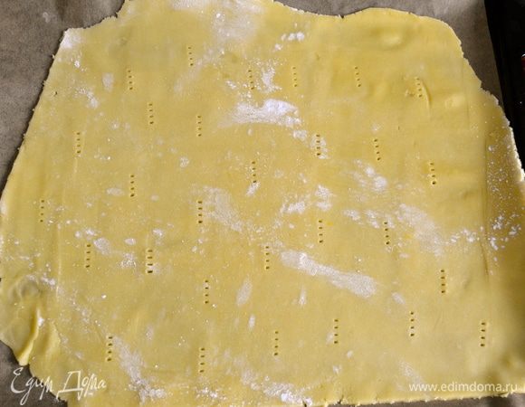 По истечении указанного времени взять две трети охлажденного теста и раскатать в пласт прямоугольной формы. Очень осторожно перенести раскатанное тесто на противень, застеленный пекарской бумагой. Наколоть поверхность вилкой и убрать в холодильник снова на 30 минут.