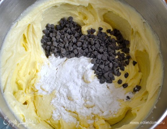 Отдельно взбить яичные белки в пену со щепоткой соли. Аккуратно всыпать 50 г оставшейся сахарной пудры. Взбивать до плотных пиков. В творожную массу аккуратно добавить шоколадные капли и крахмал (в оригинале вместо шоколада добавляется изюм).