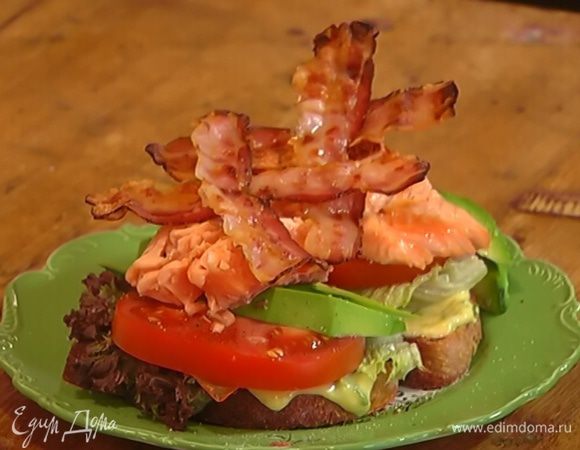 Поджаренные куски хлеба намазать майонезом, разложить на них салатные листья, кружки помидора и авокадо, посолить, поперчить, сверху выложить рыбу и бекон.