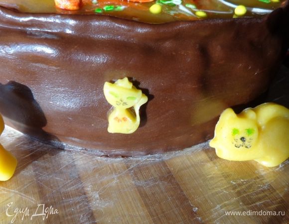 Смазать бока кремом, выровнять все неровности. Охладить. Раскатать шокомастику  и приклеить ее к боковине торта, формируя стенку кастрюли. Излишки аккуратно обрезать. Сделать ручки для кастрюли.  Охладить торт. Марципановые котики были выкрадены и съедены, как только я отвернулась...:-)