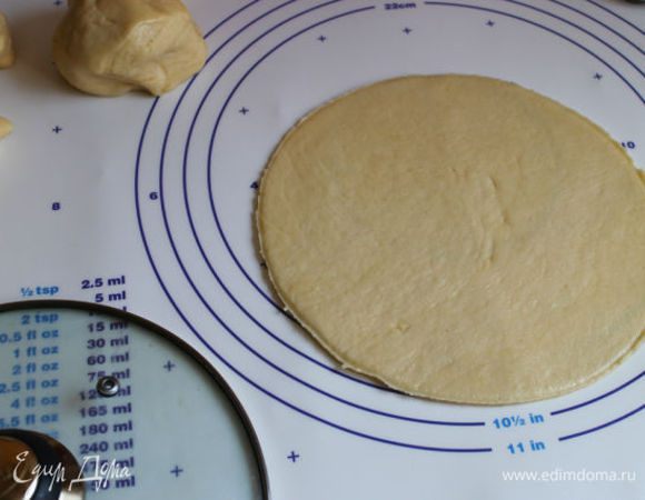 Займемся тестом, разделим его на 8 частей. Раскатываем одну часть очень тонко и вырезаем крышкой круг диаметром 20 см. Кладем его на лист с бумагой. Смазываем его нашей апельсиновой начинкой (примерно 2 ч. л.) и посыпаем сахаром слегка.
