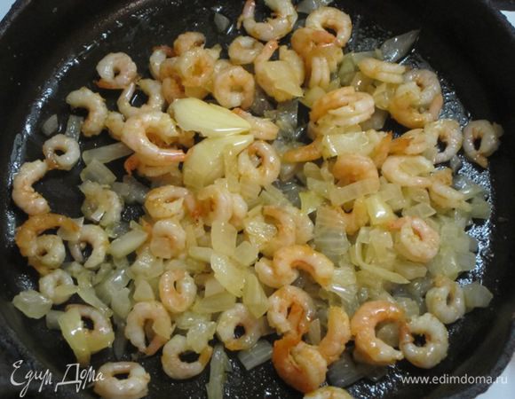 Оставить несколько креветок для украшения, а остальные выложить на сковороду к луку с чесноком.