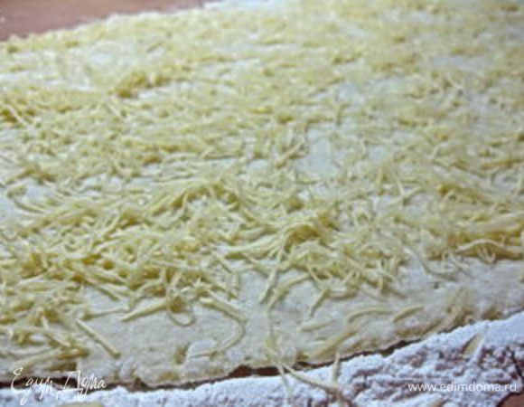 Стол посыпать мукой, выложить картофельное тесто и раскатать в большой тонкий прямоугольник. Сверху посыпать сыром.