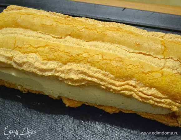 Положить первый бисквит на разделочную доску, рельефной стороной вниз.
Крем, если делали в квадратной форме, разрежьте напополам или под размеры ваших полосок. Положите на одну полоску бисквита и накройте второй.
