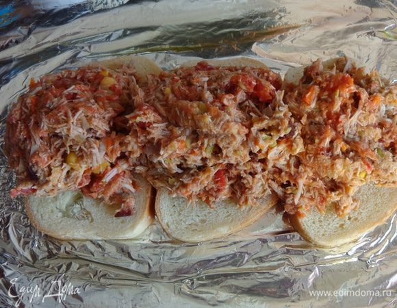 На противень, застеленный фольгой и смазанный маслом уложить несколько кусочков хлеба, на них выложить фарш.