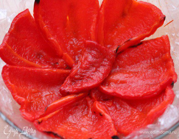 Круглую чашку выстелить пленкой, чтобы края свисали по краям. Острым ножом сделать несколько надрезов. Поместить кусочки запеченного  перца так, чтобы они расположились узким концом к центру миски.