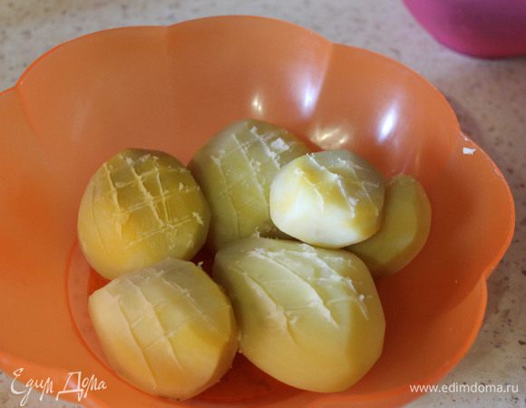 Через 10 минут слить воду, картошечку переложить в другую посуду, остудить и кончиком ножа сделать небольшие надрезы в виде сеточки.