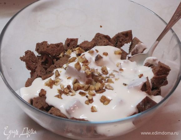 К кубикам коржа добавить крем из сметаны и орехи. Аккуратно перемешать.