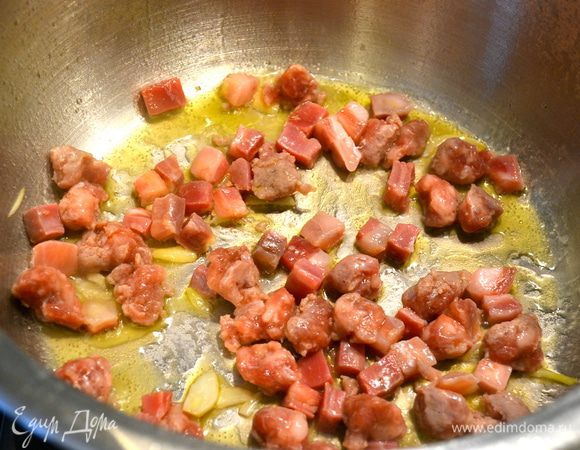 Как только бульон немного выпариться, положить в кастрюлю нарезанные бекон (грудинку) и колбаску. Обжарить, помешивая, минут 5.