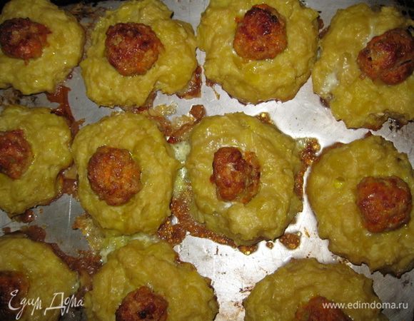Руки смазать растительным маслом, из картофеля сформировать лепешки, выложить их на смазанный растительным маслом противень.
В каждую лепешку вложить фрикадельку. Чтобы проще было вложить фрикадельку, можно взять чайную ложку, смочите ее в воде и слегка углубить в картофель. Выложить туда фрикадельки. 
Смазать гнездышки взбитым яйцом.
Поставьте в разогретую до 200 С духовку на 15-20 минут.
Подавать на листьях салата с  майонезом . 