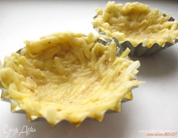 Формочки для кексов щедро смазать сливочным маслом и равномерно распределить по формочкам, чтобы получились картофельные кокотницы.